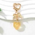 Close-up of cute UV plated strawberry keychain with golden bow and heart clasp - UV Yellow