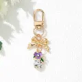Macro view of elegant golden bow keychain with purple flower and faceted crystal pendant - Purple
