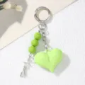 Detailed macro view showing the glossy green acrylic heart and silver star charm of the keychain - Green