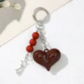 Macro view of dark brown heart keychain featuring red beads and a silver star charm - Burgundy