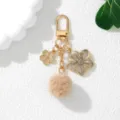 Detailed close-up of a Japanese style cherry blossom keychain with a soft tan pom-pom - Khaki