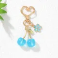Detailansicht eines blauen Kirsch-Schlüsselanhängers mit herzförmigem goldener Verschluss. - Seeblau