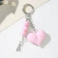 Close-up view of a pink acrylic heart keychain with beads and silver star charm pendant - Pink