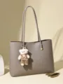 Elegante graue Kunstleder-Tragetasche mit Plüschbären-Schlüsselanhänger und langen Trägern - Bär Anhänger Stil (716.582416) / Grau