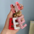 Close-up of sparkling rhinestone alphabet E keychains in red, silver, and pink - Pink Rhinestone E