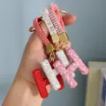 Close-up of sparkling full-diamond H-letter keychains in red, silver, and pink. - Pink Rhinestone H