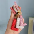 Detailed view of three rhinestone-encrusted 'L' initial keychains in red, silver, and pink - Pink Rhinestone L