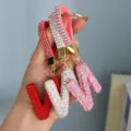Close-up of sparkly rhinestone English alphabet keychains in red, white, and pink - Pink Rhinestone N
