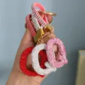 Close-up of sparkling rhinestone letter Q keychains in red, white, and pink - Pink Rhinestone Q