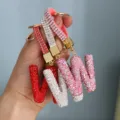 Hand-held view of sparkling rhinestone-encrusted 'W' initial keychains in multiple colors - Initial W Style / Pink