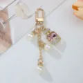 Close-up of elegant gold keychain with faux pearls and pink rhinestone perfume bottle charm - Pink