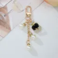 Detailed view of fashion keychain with pearls and rhinestone perfume bottle pendant - Black