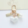 Detailed view of iridescent heart and pearl charms on a stylish golden alloy keychain - Heart Pearl Design