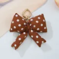 Detailed macro view of the brown polka dot fabric bow and heart-shaped gold clasp - Brown