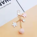 Close-up detail of Japanese style floral and pink fuzzy pom-pom keychain pendant charm - Cherry Blossom Metal Clasp