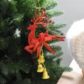 Vista detallada de un adorno navideño de reno rojo con campanas doradas en un árbol. - Colgante de Reno / 13cm / Rojo