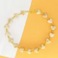 Detailed macro view of vintage marbled resin heart necklace with gold beads and metal clasp. - Beige Necklace