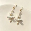 Detailed close-up view of elegant white ceramic bird earrings with delicate pearls. - White