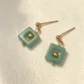 Primer plano de pendientes cuadrados minimalistas de piedra natural verde en tono oro - Aventurina Verde