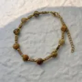 Detailed view of natural stone beads and gold stainless steel chain on a white background. - Bracelet / Picture Jasper