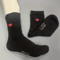 Detailed view of black merino wool socks with red heart embroidery and woven text detail. - S36-38 / Black 1