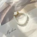Close-up of bohemian beaded ring with shell star and gold accents on soft fabric - Elastic Style / White