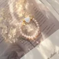 Detailed view of an elegant crystal beaded elastic ring featuring a white shell heart - Stretch / Pink