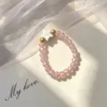 Close-up of a pink faceted glass beaded elastic ring with a white star shell charm - Elastic Style / Pink