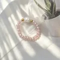 Nahaufnahme des handgefertigten Armbands aus rosa Glasperlen und Süßwasserperlen im Sonnenlicht - Rosa