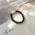 Close-up of a Bohemian elastic beaded ring with black faceted beads and a white shell star - Elastic Style / Black