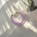 Detailaufnahme eines handgefertigten elastischen Rings mit lila Glasperlen und Naturperle - Lila
