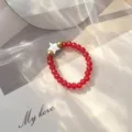 Close-up of a Bohemian red glass beaded ring featuring a white shell star detail - Elastic Style / Red
