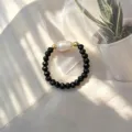 Makro-Detail des handgefertigten Perlenrings mit schwarzen Facettenperlen und Barockperle - Schwarz