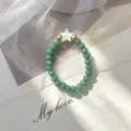 Close-up of bohemian green glass beaded ring featuring a white shell star - Elastic Style / Green