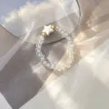 Close-up of clear glass beaded ring with white shell star on dreamy fabric background. - Elastic Style / Clear
