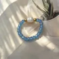 Detailansicht von blauen Glasperlen und einer Süßwasserperle auf einem Stretchring. - Aqua