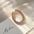 Detailed macro view of bohemian elastic ring with amber glass beads and white shell star detail - Elastic Style / Champagne