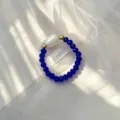 Nahaufnahme eines elastischen Rings mit natürlicher Süßwasserperle und blauen Glasperlen - Blau