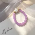 Detailed view of purple beaded ring with shell star charm and golden beads for women. - Elastic Style / Purple