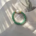 Detailaufnahme eines handgefertigten elastischen Rings mit Barockperle und Perlen - Grün