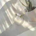 Macro view of minimalist handmade elastic beaded ring with a white shell fish charm - Shell Fish (Stretch) / Clear