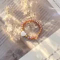 Detail showing white shell heart charm on champagne crystal glass beaded elastic ring - Stretch / Champagne