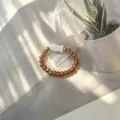 Detail view of handmade elastic ring with amber glass beads and white shell fish charm. - Shell Fish (Stretch) / Champagne