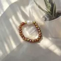 Detailansicht eines handgefertigten Perlenrings mit Bernsteinglasperlen und Perle. - Champagner