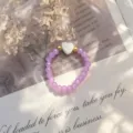 Elegant handmade purple crystal beaded ring featuring a white shell heart center detail. - Stretch / Purple