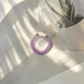 Detailed macro view of a purple glass beaded elastic ring with a shell fish charm. - Shell Fish (Stretch) / Purple
