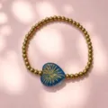 Detailansicht eines blau glasierten Herzanhängers an einem vergoldeten Edelstahlarmband - Radiating love-blue