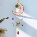 Detail of crystal suncatcher with moon and butterfly charms casting rainbow light - Pink Crystal / 40CM
