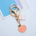 Detailed close-up of a cute gold-tone rabbit and peach enamel keychain pendant - Single OPP Bag Packaging / Peach and Rabbit