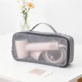 Borsa a rete grigia per riporre un asciugacapelli rosa su un tavolo bianco - Grigio
